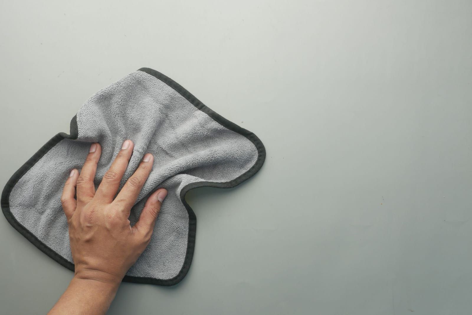 Main essuyant une surface avec une microfibre